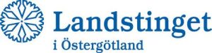 Rexuma vårdrumspanel Blå logotyp med en snöflingeliknande symbol till vänster och texten Landstinget i Östergötland till höger, representerar en regional sjukvårdshuvudman i Östergötland, Sverige - syns ofta på sjukhus eller i närheten av Vårdrumspanelens installationer.