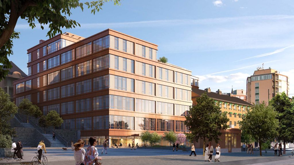 Rexuma vårdrumspanel Ett modernt sjukhus i glas och tegel med flera våningar står en solig dag, omgivet av träd och människor som promenerar, cyklar och umgås på ett torg i staden. I bakgrunden syns andra byggnader och en klarblå himmel.