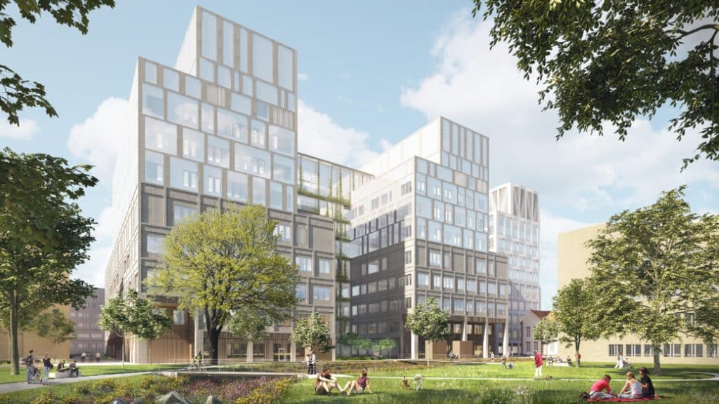 Rexuma vårdrumspanel Moderna sjukhus i glas i flera våningar omgivna av gröna gräsmattor och träd, med människor som sitter och kopplar av på gräset en solig dag. Himlen är blå med några få moln.