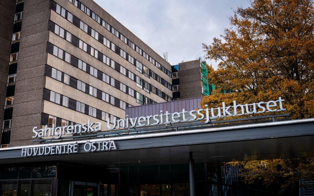 Rexuma vårdrumspanel En stor sjukhusbyggnad med skylten ”Sahlgrenska Universitetssjukhuset Huvudentré Östra” ovanför huvudingången. Höstträd med gula löv står intill den moderna flervåningsbyggnaden.