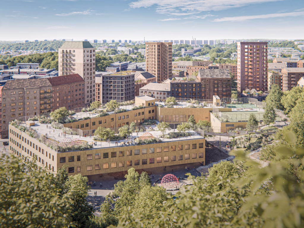 Rexuma vårdrumspanel Ett stadslandskap med moderna, medelhöga tegelbyggnader omgivna av träd, med takträdgårdar och rekreationsområden, mot bakgrund av en tät stadsmiljö under en delvis molnig himmel.